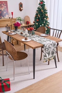 Dettaglio del runner da tavolo verde salvia con motivi floreali e nappe decorative