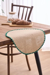 Detail of natural jute placemat featuring dark green crochet lace edging on wooden table