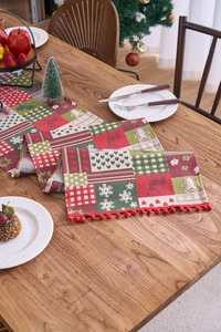 Close-up of festive Christmas table runner with reindeer patterns and red pom-pom trim