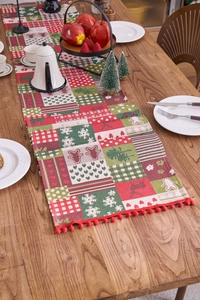 Close-up of woven Christmas table runner with festive reindeer patterns and red pompoms