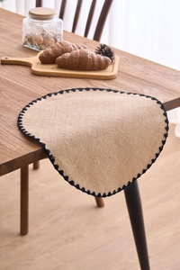 Detail of jute placemat with black crochet wavy edges on a rustic wooden dining table