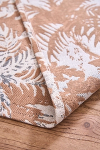 Dettaglio del runner da tavola jacquard spesso con motivi di foglie tropicali e nappe