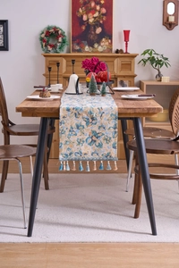 Detail of blue jacquard table runner with floral patterns and tassel pendants