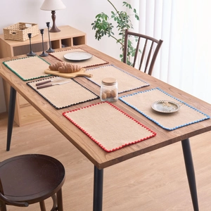 Sets de table en jute tissés main avec bords festonnés colorés sur une table en bois