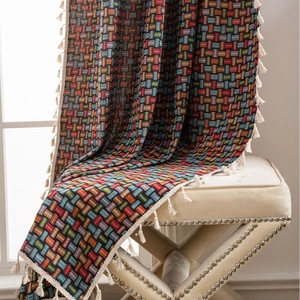 Couverture jacquard géométrique colorée avec pompons blancs sur tabouret vintage