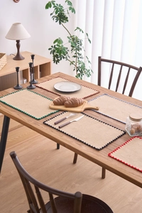 Gros plan de sets de table en jute tissé avec bordures au crochet sur table en bois
