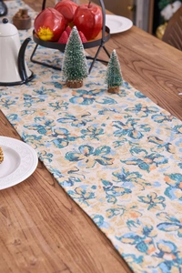 Close-up of jacquard table runner with blue floral patterns and tassel edge on wood table