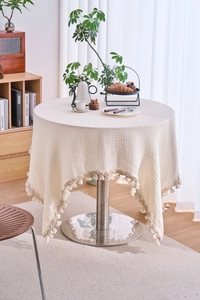 Detailed view of white waffle weave tablecloth fabric featuring soft fringe tassels