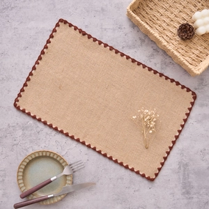 Détail d'un set de table en jute naturelle avec bordure festonnée crochetée marron foncé