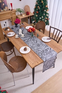 Detailed view of paisley table runner with high contrast pattern on wooden dining table