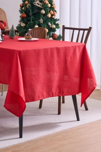 Detail of red festive tablecloth featuring woven texture on a wooden dining table setup
