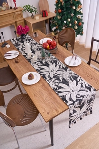 Dettaglio di runner da tavolo bohémien con motivi tropicali e eleganti nappe nere