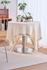 Macro detail of creamy white waffle weave tablecloth with decorative fringe tassels