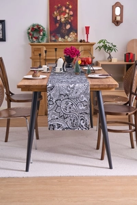 Close-up of black and white paisley pattern jacquard table runner on a wooden table