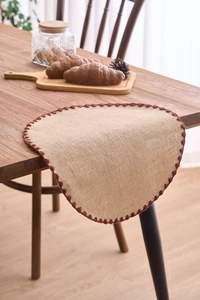 Close-up of linen placemat featuring intricate brown crochet lace edge on a wooden table