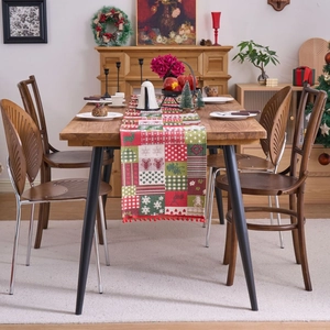Christmas table runner with deer patterns and red pompom tassels on wooden dining table
