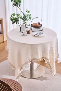 Close-up of beige waffle weave tablecloth texture with decorative tassel fringe details