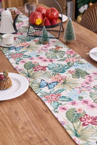 Detail of red jacquard table runner with tropical leaves and butterfly patterns on wood