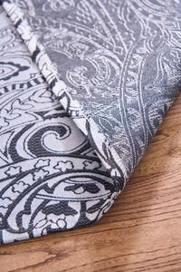 Detailed macro view of woven grey and white paisley jacquard fabric on wooden table