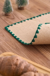 Vue détaillée d'un chemin de table en jute avec bordure au crochet vert foncé