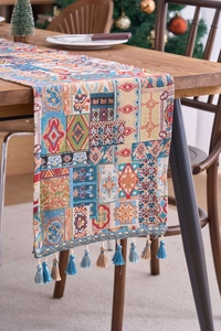 Dettaglio del runner da tavola jacquard rosso con motivi etnici e nappine decorative