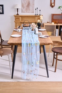 Detail of light blue lace table runner featuring delicate colorful floral embroidery