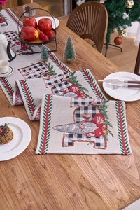 Detail of jacquard table runner with Santa Claus motif and Believe text on wood table