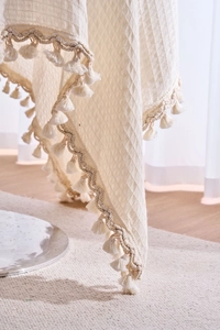 Close-up of cream waffle weave tablecloth with detailed handmade tassel fringe edges