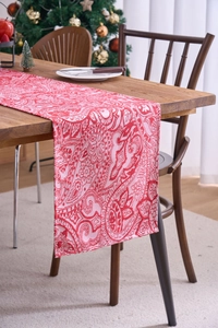 Close-up of red and beige Paisley jacquard table runner on a dark wood festive table