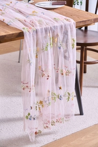 Detail of pink lace table runner with violet and forget-me-not flower embroidery