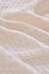 Detailed macro view of cream waffle weave fabric texture with soft geometric patterns