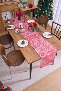 Detailed close-up of red and white paisley table runner in a cozy Christmas dining setting