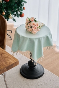 Close-up of mint green rectangular tablecloth featuring ivory tassels and linen texture
