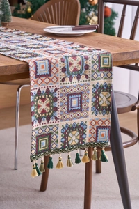 Detail of bohemian jacquard table runner with geometric patterns and fringe tassels