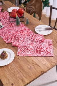 Close-up of red and white paisley jacquard table runner on a rustic wooden dining table