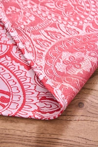 Detail of red and white jacquard table runner with intricate mandala patterns and fine texture