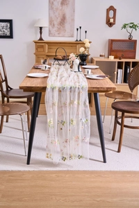 Close-up detail of french lace table runner featuring colorful floral embroidery on mesh fabric