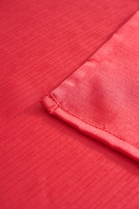 Close-up of the red festive tablecloth showing durable hemmed edges and grid texture