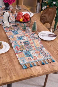 Dettaglio del runner da tavola boho con trama geometrica spessa e nappe colorate