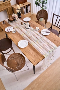 Detailed close-up of white mesh lace table runner with colorful floral embroidery