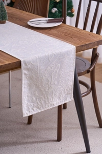 Macro shot of off-white lace table runner with intricate paisley and floral patterns