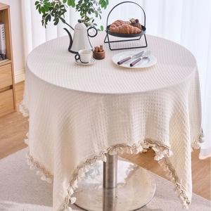 Creamy white round waffle weave tablecloth with decorative tassel fringe edges
