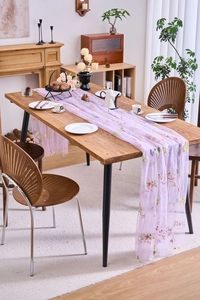 Detail of light purple lace table runner with floral embroidery on wooden dining table