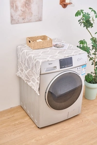 Détail du protège-poussière gris à motifs géométriques avec pompons décoratifs