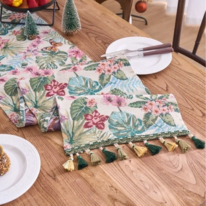 Nordic floral jacquard table runner with pink flowers and green tassels on wooden table