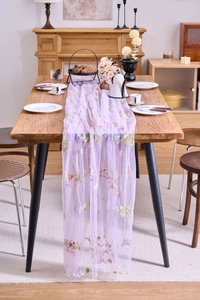 Detail of lavender lace table runner with multi-colored floral embroidery on wooden table