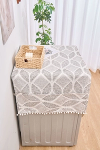 Détail du motif feuille géométrique et des pompons blancs sur la housse en coton lin