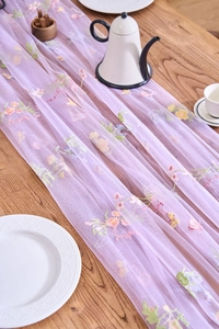 Close-up of vintage lace table runner with colorful floral embroidery on purple tulle