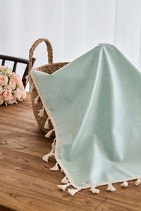 Detail of mint green waterproof tablecloth showing delicate white fringe and linen texture