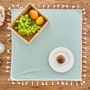 Close-up of mint green TPU waterproof tablecloth with decorative white tassels on wood